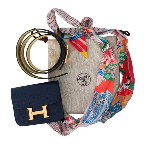 HERMÈS CONSTANCE BELTED WALLET IN BLUE EVERCOLOR LEATHER WITH SILK TWILLY: HERMÈS CONSTANCE BELTED WALLET IN BLUE EVERCOLOR LEATHER WITH SILK TWILLY KL NTOO The Constance wallet is a beautiful navy color, with gold hardware. The Silk twilly is colorful and is depicted with 
