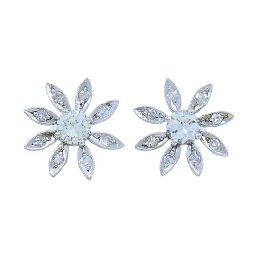 DIAMOND FLORAL STUD EARRINGS 14K GOLD ESTATE JEWELRY: 14 karat White Gold Diamond Stud Earrings A pair of diamond floral stud earrings made of 14k gold. Each earring showcases a central round brilliant cut diamond surrounded with a halo of petal-shaped e