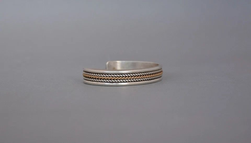 VINTAGE NAVAJO STERLING SILVER WITH 12 KT.GF GOLD BRACELET 3/8" BAND - SIZE 7": VINTAGE NAVAJO STERLING SILVER WITH 12 KT.GF GOLD BRACELET 3/8" BAND - SIZE 7" This bracelet has been beautifully crafted by Navajo silversmith Daniel Mike. It has 2 rows of twisted sterling silver wi