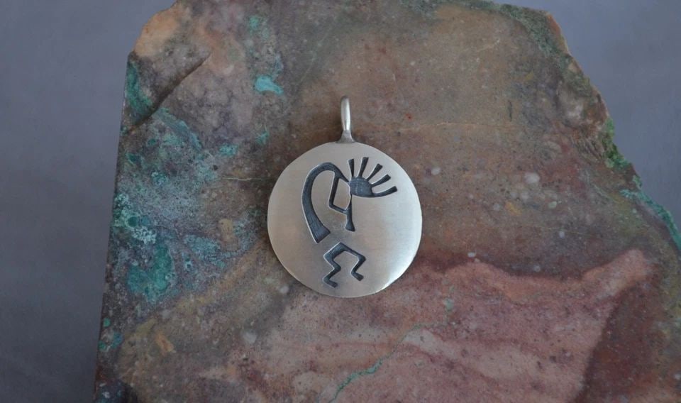 MANUEL HOYUNGOWA (1953-2011) - HOPI SILVER ROUND PENDANT - FLUTE PLAYER - 1.25": MANUEL HOYUNGOWA (1953-2011) - HOPI SILVER ROUND PENDANT - FLUTE PLAYER - 1.25" This sterling silver pendant has been beautifully crafted by the Hopi artists Manuel and Karen Hoyungwa. The pendant sho
