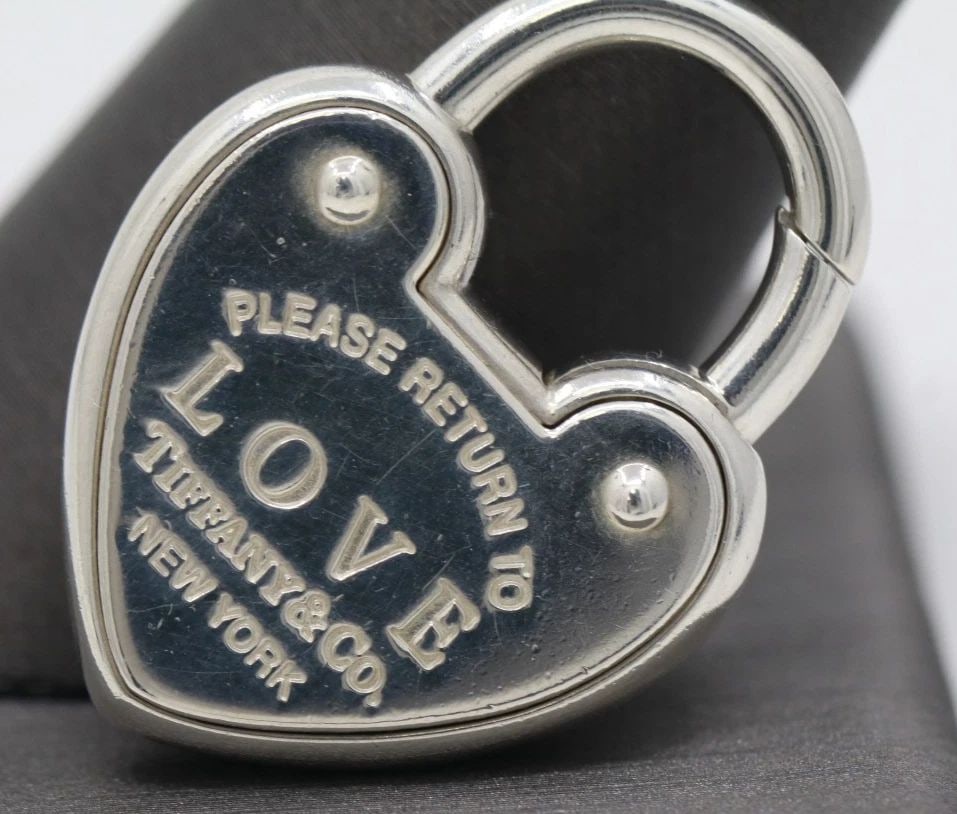 RETURN TO TIFFANY & CO. STERLING SILVER HEART PADLOCK CHARM PENDANT: RETURN TO TIFFANY & CO. STERLING SILVER HEART PADLOCK CHARM PENDANT Description Return to Tiffany & Co. Sterling Silver Heart Padlock Charm Pendant Charm/pendant is in good condition. May show signs o