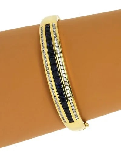 DIAMOND SAPPHIRE GOLD BRACELET 18K YELLOW BANGLE: DIAMOND SAPPHIRE GOLD BRACELET 18K YELLOW BANGLE The Diamond Sapphire Gold Bracelet is a stunning piece of fine jewelry made of natural white diamond and intense blue sapphire gemstones. The oval-shap