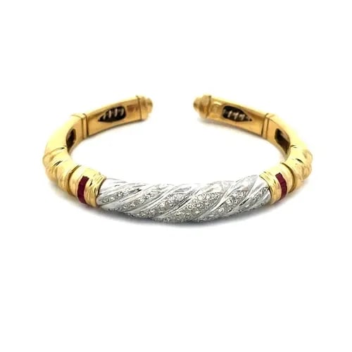DIAMOND GOLD CUFF BRACELET RUBY 18K TWO TONE PAVE SET: DIAMOND GOLD CUFF BRACELET RUBY 18K TWO TONE PAVE SET This stunning cuff bracelet is crafted from 18k yellow gold with white gold accent featuring a swirl pattern in white gold on the front center wit