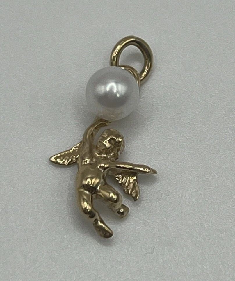 14K YELLOW GOLD ANGEL CHARM WITH PEARL: 14K YELLOW GOLD ANGEL CHARM WITH PEARL 14K YELLOW GOLD ANGEL CHARM WITH PEARL This 14K yellow gold angel charm is a stunning piece of fine jewelry that is sure to catch the eye. The charm features a b