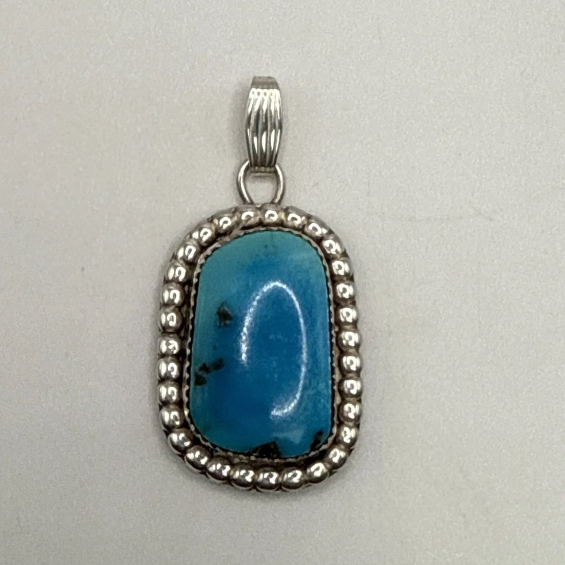 STERLING SILVER & TURQUOISE PENDANT: STERLING SILVER & TURQUOISE PENDANT This Native American sterling silver pendant features a beautiful turquoise stone in a vibrant blue color. The pendant is crafted with 925 sterling silver and showc