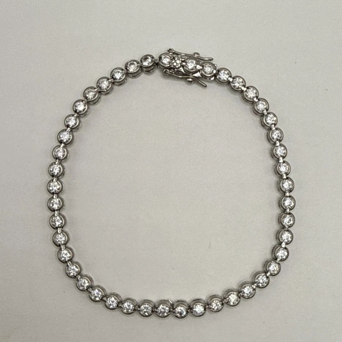 8" STERLING SILVER TENNIS BRACELET WITH BEZEL SET ROUND COLORLESS STONES: 8" STERLING SILVER TENNIS BRACELET WITH BEZEL SET ROUND COLORLESS STONES This 8" Sterling Silver Tennis Bracelet features a classy design with bezel set colorless round stones, exuding elegance and so