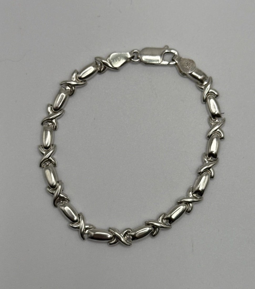 STERLING SILVER 7" X BRACELET 6.2 GRAMS: STERLING SILVER 7" X BRACELET 6.2 GRAMS The product is a 7" x bracelet made of sterling silver with a purity of 925. It is designed in a chain style, with no main stone. This elegant and classic brace