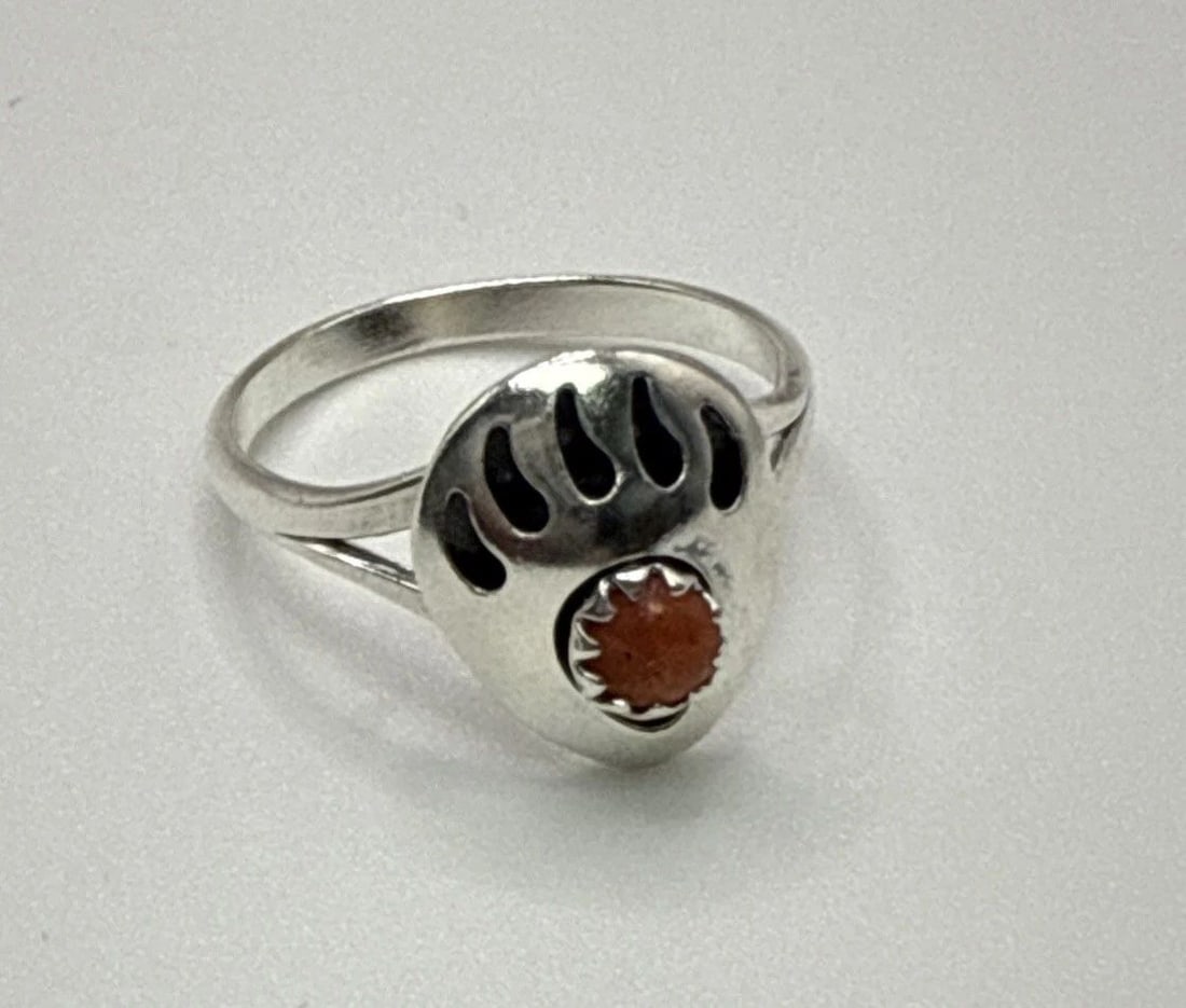 NAVAJO SERLING SILVER SIZE 5.5 BEAR PAW RING WITH CORAL STONE: NAVAJO SERLING SILVER SIZE 5.5 BEAR PAW RING WITH CORAL STONE The product is a Navajo sterling silver size 5.5 bear paw ring with a coral stone. This unique piece of jewelry showcases a traditional Na