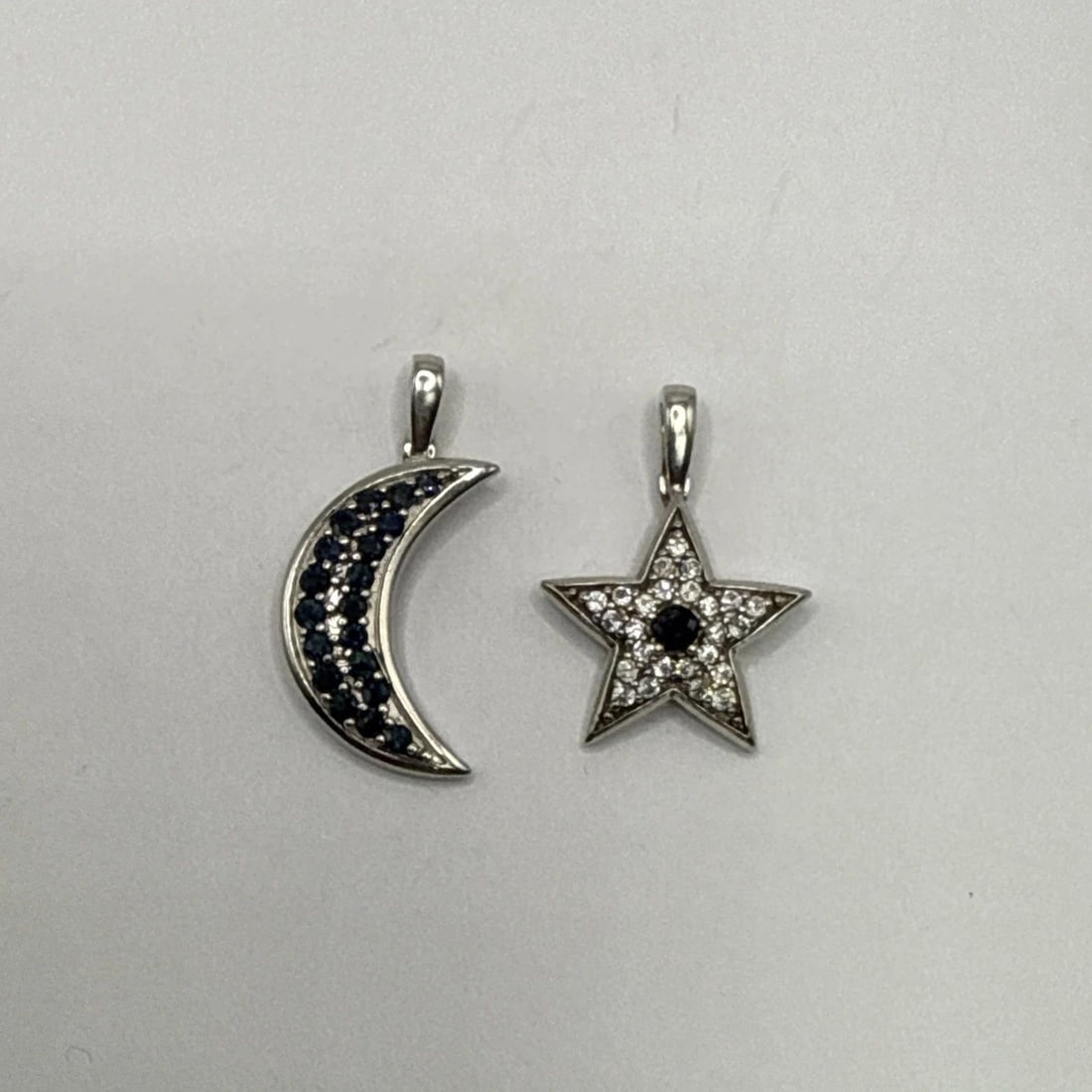 STERLING SILVER MOON AND STAR CHARMS WITH BLUE AND COLORLESS STONES: STERLING SILVER MOON AND STAR CHARMS WITH BLUE AND COLORLESS STONES This product is a set of sterling silver moon and star charms adorned with blue and colorless stones. Each charm is made of high-qua