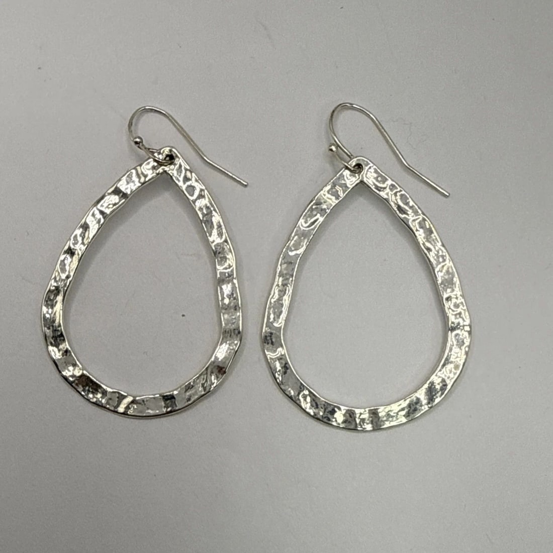 COSTUME HAMMERED SILVER TEARDROP SHAPED EARRINGS: COSTUME HAMMERED SILVER TEARDROP SHAPED EARRINGS These Costume Hammered Silver Teardrop Shaped Earrings are a stylish and elegant addition to any outfit. The teardrop shape adds a feminine touch, whil