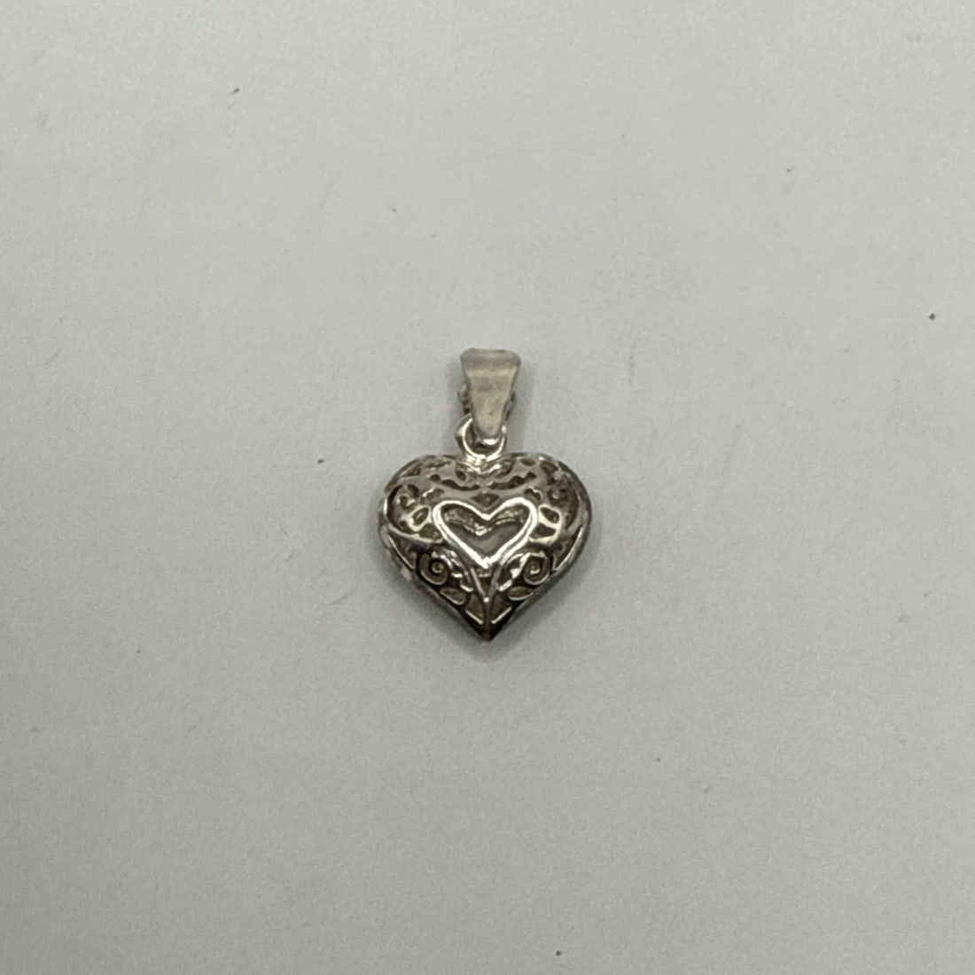 SILVER HEART CHARM 2.4 GRAMS: SILVER HEART CHARM 2.4 GRAMS The Silver Heart Charm is a fine jewelry piece made of 925 sterling silver, weighing 2.4 grams. This charming pendant features a heart shape design, perfect for adding a