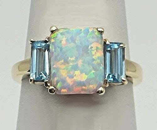 10K GOLD RING WITH LAB-CREATED OPAL AND TWO BLUE TOPAZ (SIZE 7) 2.7 GRAM: 10K GOLD RING WITH LAB-CREATED OPAL AND TWO BLUE TOPAZ SIZE: 7 10k Gold Ring with Lab-Created Opal and two Blue Topaz Condition: Used, the lab created Opal has a chip on the bottom of it, has been mar