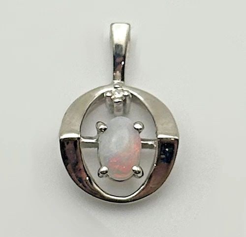 10K WHITE GOLD ROUND PENDANT WITH OPAL AND A 0.01CT DIAMOND 1.5 GRAMS: 10k White Gold Round Pendant with Opal and a 0.01ct Diamond Condition: Used Material: 10k White Gold Pendant Size: 16.5mm x 10mm , measured at it's furthest points including the bail Total Weight: 1.5