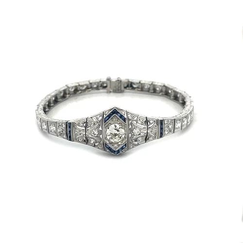 PLATINUM ART DECO BRACELET 3.5CT DIAMOND FLORAL CENTERPIECE CUBE LINKS: The platinum Art Deco bracelet is a stunning piece of antique jewelry featuring a floral centerpiece with a sparkling diamonds accented with blue colored stones, the milgrain filigree asymmetrical sha