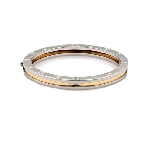 BULGARI B ZERO-1 BANGLE STEEL & 18K YELLOW GOLD ENGRAVED SIDES: BULGARI B ZERO-1 BANGLE STEEL & 18K YELLOW GOLD ENGRAVED SIDES This chic authentic bracelet is by Bvlgari from the B Zero.1 Collection. It is a small size and crafted from stainless steel with 18k yel