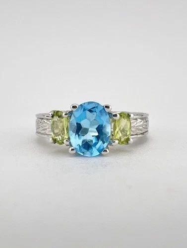 DESIGNER 10K WHITE GOLD BLUE TOPAZ & GREEN PERIDOT ETCHED WOMEN'S RING: Designer 10k White Gold Blue Topaz & Green Peridot Etched Women's Ring Ring Size: 7 - Can Be Resized Metal: 10k White Gold - Hallmarked Weight is 5.3 Grams on my scale Ring is 7mm (Over 1/4") Wide In 