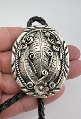 VTG NAVAJO STERLING SILVER DEEP STAMPED OVAL FLORAL FEATHER CONCHO BOLO TIE: VTG NAVAJO STERLING SILVER DEEP STAMPED OVAL FLORAL FEATHER CONCHO BOLO TIE Vtg Navajo Sterling Silver Deep Stamped Oval Floral Feather Concho Bolo Tie Size: Over 2 1/4" Tall by 1 7/8" Wide Weight is 