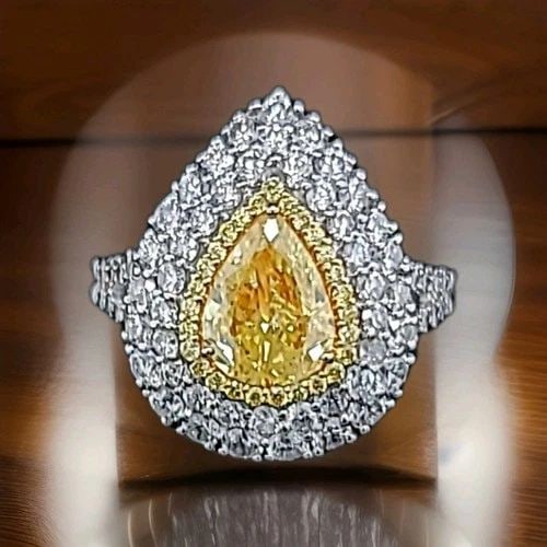 18K WHITE GOLD ENGAGEMENT RING 2.42CT. NATURAL FANCY YELLOW DIAMOND PEAR SHAPE: 18K WHITE GOLD ENGAGEMENT RING 2.42CT. NATURAL FANCY YELLOW DIAMOND PEAR SHAPE This stunning 18k white gold engagement ring features a 1.05ct pear-shaped natural fancy yellow diamond, surrounded by sp