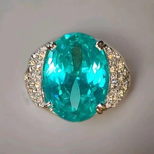 14K WHITE YELLOW GOLD COCKTAIL RING 16.53CT. NEON BLUE OVAL TOURMALINE DIAMOND: 14K WHITE YELLOW GOLD COCKTAIL RING 16.53CT. LAB GROWN PARAIBA TOURMALINE OVAL This 14K white gold cocktail ring features a stunning 16.53CT lab-grown Paraiba Tourmaline with an oval cut, accented wit