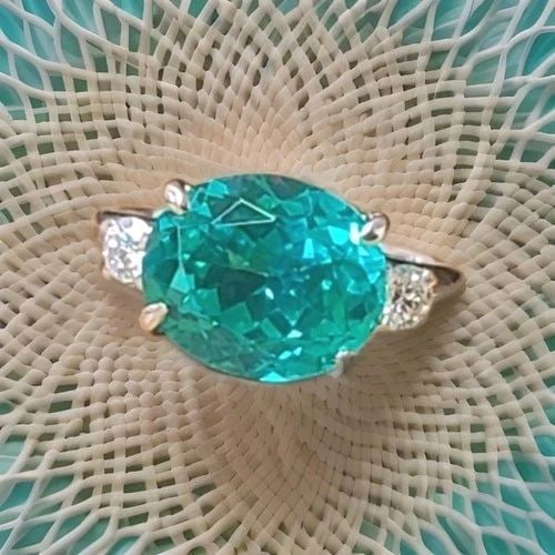 VINTAGE PLATINUM ENGAGEMENT RING 7.27CT. BLUE NEON TOURMALINE OVAL SHAPE: VINTAGE PLATINUM ENGAGEMENT RING 7.27CT. BLUE NEON TOURMALINE OVAL SHAPE This exquisite vintage ring showcases a 7.27-carat oval-cut lab-grown blue tourmaline (12 × 10 mm) with a vibrant neon blue co