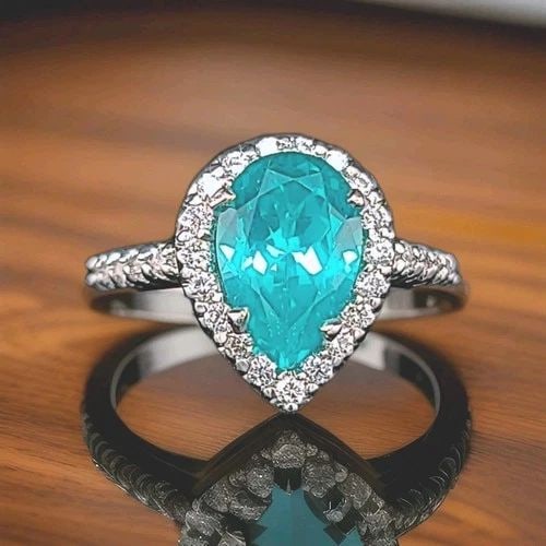 18K WHITE GOLD ENGAGEMENT RING 4.76CT. BLUE NEON TOURMALINE PEAR SHAPE: 18K WHITE GOLD ENGAGEMENT RING 4.76CT. BLUE NEON TOURMALINE PEAR SHAPE Elegant vintage-inspired engagement ring crafted in solid 18K white gold, featuring a stunning pear-shaped lab-grown Neon Blue To