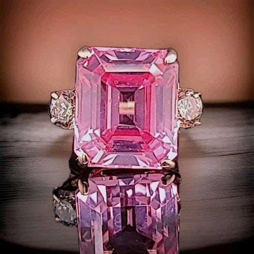 14K ROSE GOLD ENGAGEMENT RING 12.26CT. LAB GROWN PEACH SAPPHIRE EMERALD SHAPE: 14K ROSE GOLD ENGAGEMENT RING 12.26CT. LAB GROWN PEACH SAPPHIRE EMERALD SHAPE A stunning ring crafted in solid 14K rose gold, featuring a breathtaking emerald-cut lab-grown peach sapphire weighing app