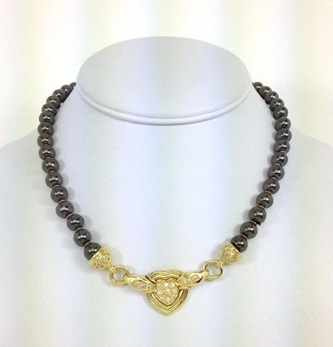 DIAMOND HEMATITE GOLD NECKLACE 18K YELLOW BEAD CHAIN HEART MOTIF: DIAMOND HEMATITE GOLD NECKLACE 18K YELLOW BEAD CHAIN HEART MOTIF This Diamond Hematite Gold Necklace features a heart-shaped pendant with a white diamond as the main stone, set in 18k yellow gold. The
