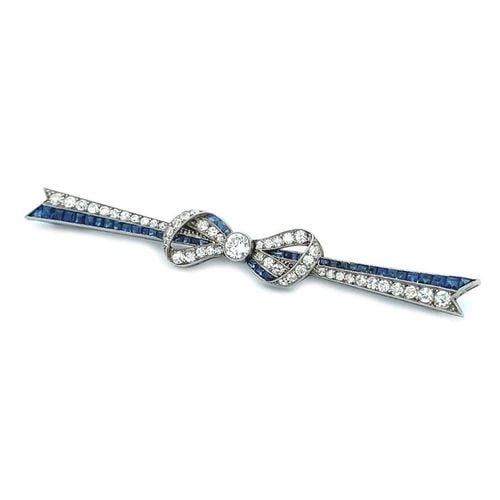 ART DECO PLATINUM DIAMOND SAPPHIRE RIBBON BOW LONG BROOCH: ART DECO PLATINUM DIAMOND SAPPHIRE RIBBON BOW LONG BROOCH This is an elegant long ribbon bow brooch, it is crafted from platinum featuring a double strip long ribbon with a bow in the center, one stri