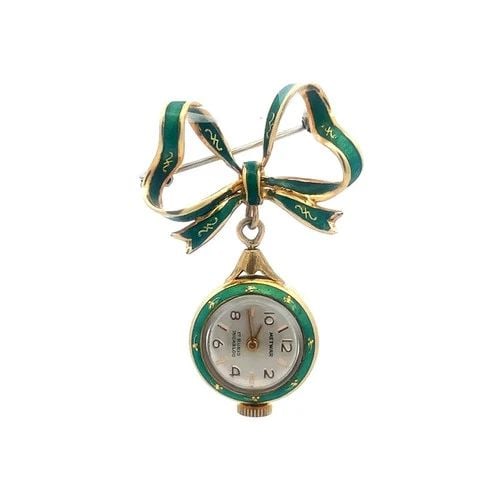 GOLD ENAMEL DANGLE WATCH BROOCH 18K YELLOW HAND WIND RIBBON BOW TOP VINTAGE: GOLD ENAMEL DANGLE WATCH BROOCH 18K YELLOW HAND WIND RIBBON BOW TOP VINTAGE This lovely vintage dangle watch brooch is crafted from 18k yellow gold, it features an 18mm round case gold and green ename