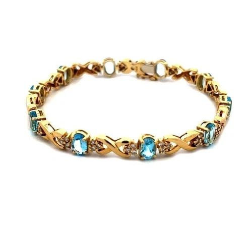 DIAMOND GOLD BRACELET 14K YELLOW BLUE TOPAZ X OVAL LINK S: 70193 DIAMOND GOLD BRACELET 14K YELLOW BLUE TOPAZ X OVAL LINK S This lovely bracelet is crafted from 14k yellow gold featuring alternating polished gold X links with oval prong set blue topaz and smal