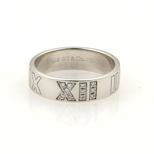 TIFFANY & CO.ATLAS GOLD RING DIAMONDS ROMAN NUMERAL 18K WHITE BAND SIZE 5: TIFFANY & CO.ATLAS GOLD RING DIAMONDS ROMAN NUMERAL 18K WHITE BAND SIZE 5 The Tiffany & Co. Atlas gold ring is a luxurious piece of fine jewelry featuring a Roman numeral design in white gold with rou