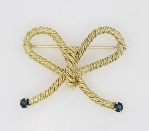 TIFFANY & CO. 18K YELLOW GOLD BLUE SAPPHIRE ROPE BOW TWIST PIN BROOCH 10.1 GR: TIFFANY & CO. 18K YELLOW GOLD BLUE SAPPHIRE ROPE BOW TWIST PIN BROOCH 10.1 GR Description Tiffany & Co. 18K Yellow Gold Blue Sapphire Rope Bow Twist Pin Brooch Pin/brooch is in good condition. May sho