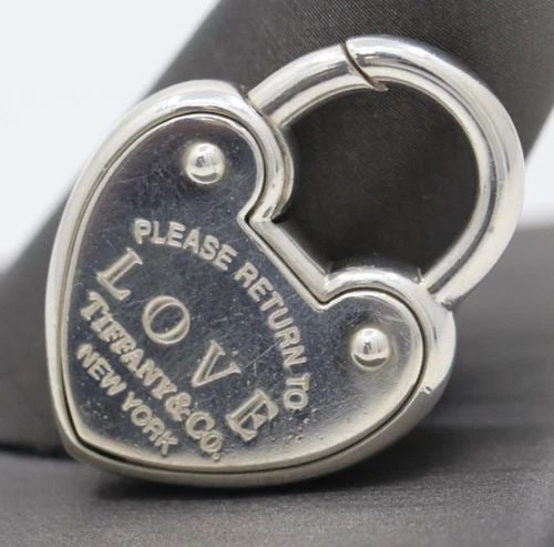 RETURN TO TIFFANY & CO. STERLING SILVER HEART PADLOCK CHARM PENDANT: RETURN TO TIFFANY & CO. STERLING SILVER HEART PADLOCK CHARM PENDANT Description Return to Tiffany & Co. Sterling Silver Heart Padlock Charm Pendant Charm/pendant is in good condition. May show signs o