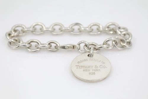 TIFFANY & CO. PLEASE RETURN TO TIFFANY ROUND TAG CIRCLE CHARM BRACELET: TIFFANY & CO. PLEASE RETURN TO TIFFANY ROUND TAG CIRCLE CHARM BRACELET Description Tiffany & Co. Please Return to Tiffany Round Tag Circle Charm Bracelet Item is in good condition. May show signs of w