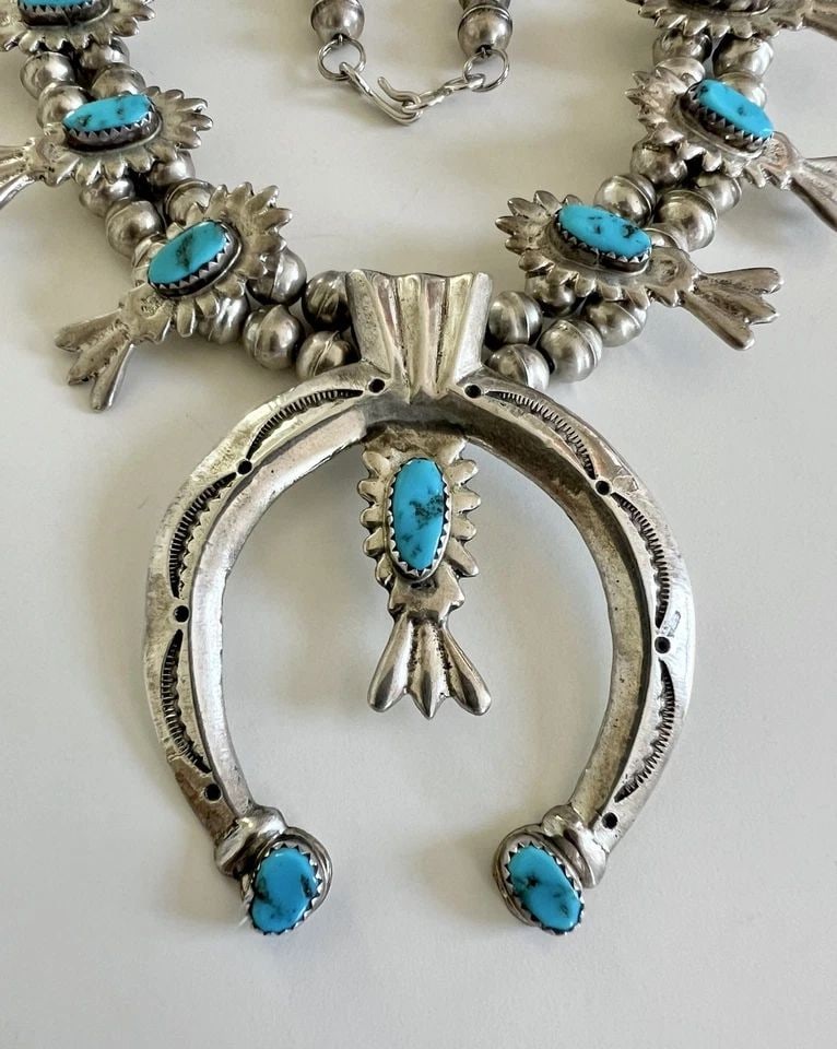 VTG NAVAJO SANDCAST STERLING SLEEPING BEAUTY TURQUOISE SQUASH BLOSSOM NECKLACE: Vtg Navajo Sandcast Sterling Silver Sleeping Beauty Turquoise Squash Blossom Necklace This Amazing necklace features huge specimens of Natural Blue Sleeping beauty Turquoise, secure in a Sawtooth beze