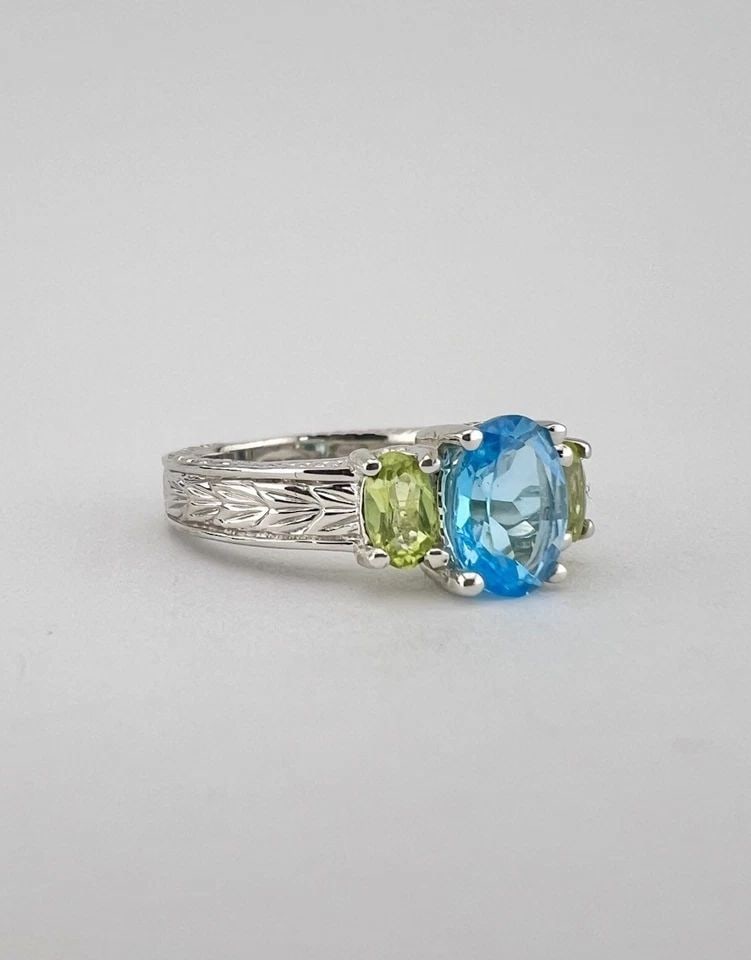 DESIGNER 10K WHITE GOLD BLUE TOPAZ & GREEN PERIDOT ETCHED WOMEN'S RING: Designer 10k White Gold Blue Topaz & Green Peridot Etched Women's Ring Ring Size: 7 - Can Be Resized Metal: 10k White Gold - Hallmarked Weight is 5.3 Grams on my scale Ring is 7mm (Over 1/4") Wide In 