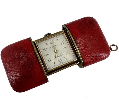 VINTAGE HERMES TRAVEL WATCH C.1960S: VINTAGE HERMES TRAVEL WATCH C.1960S A rare time piece by Hermes, a vintage travel watch. The watch set ina red leather case equipped with a slide opening mechanism. The face is square shape, with a wh