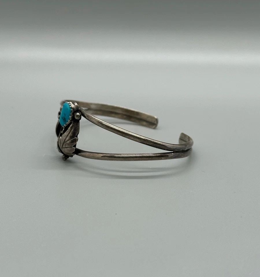 VINTAGE NAVAJO STERLING SILVER BRACELET - LEAVES TURQUOISE FLOWER - 6 1/4": VINTAGE NAVAJO STERLING SILVER BRACELET - LEAVES TURQUOISE FLOWER - 6 1/4" Item Description: This vintage Navajo Sterling silver bracelet has a silver leaf and tendrils surrounding a turquoise flower 