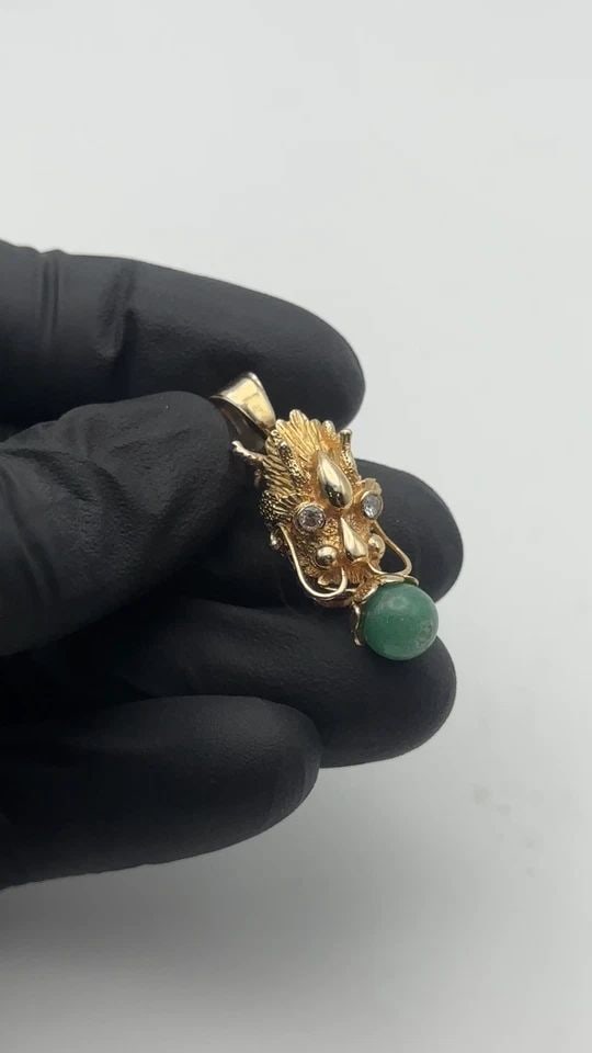 14K GOLD DRAGON HEAD PENDANT WITH 0.12CTW DIAMONDS AND JADE BALL BEAD 9.2 GRAMS: 14k Gold Dragon Head Pendant with 0.12cts of Diamond and Jade Ball Bead Condition: Used, has marks but also has been cleaned by our in house Jewelers Material: 14k Yellow Gold Pendant Size: 43mm total