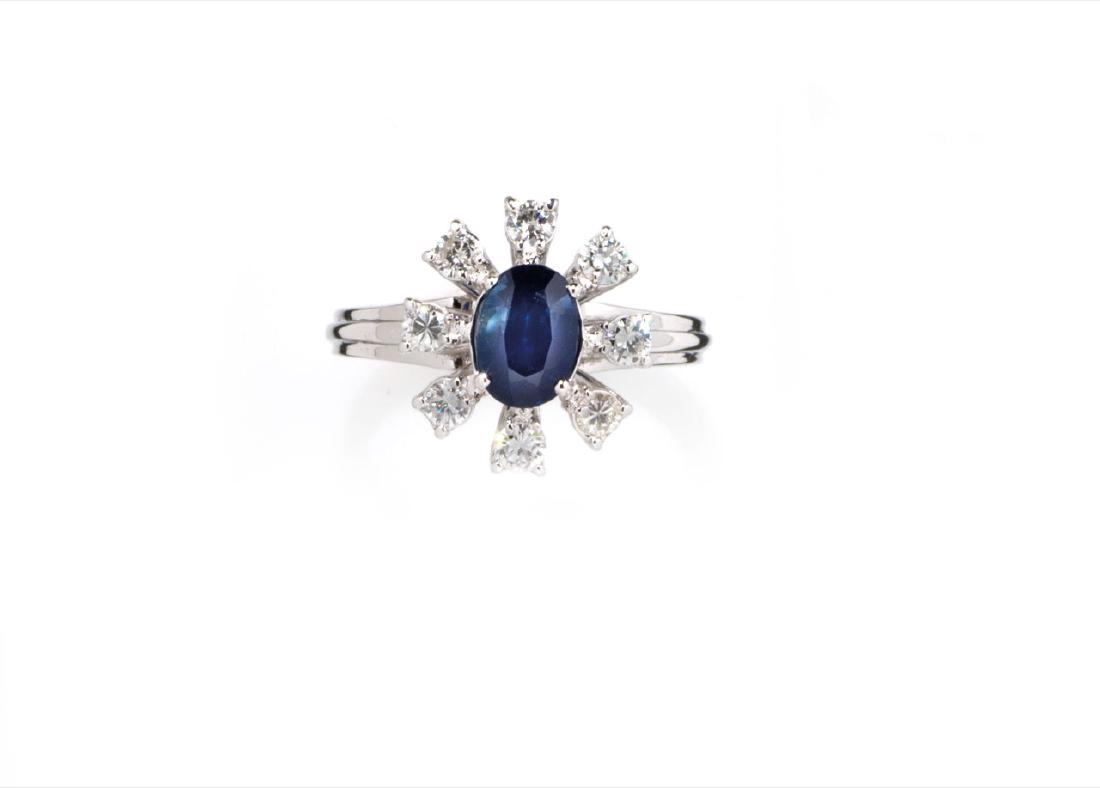 WHITE GOLD RING WITH SAPPHIRE AND DIAMONDS, CIRCA 1960: ANELLO IN ZAFFIRO E DIAMANTI, CIRCA 1960 in oro bianco con motivo a margherita in griffes a filo centrato da zaffiro taglio ovale ct 1,40 ca, ornato da diamanti taglio brilla