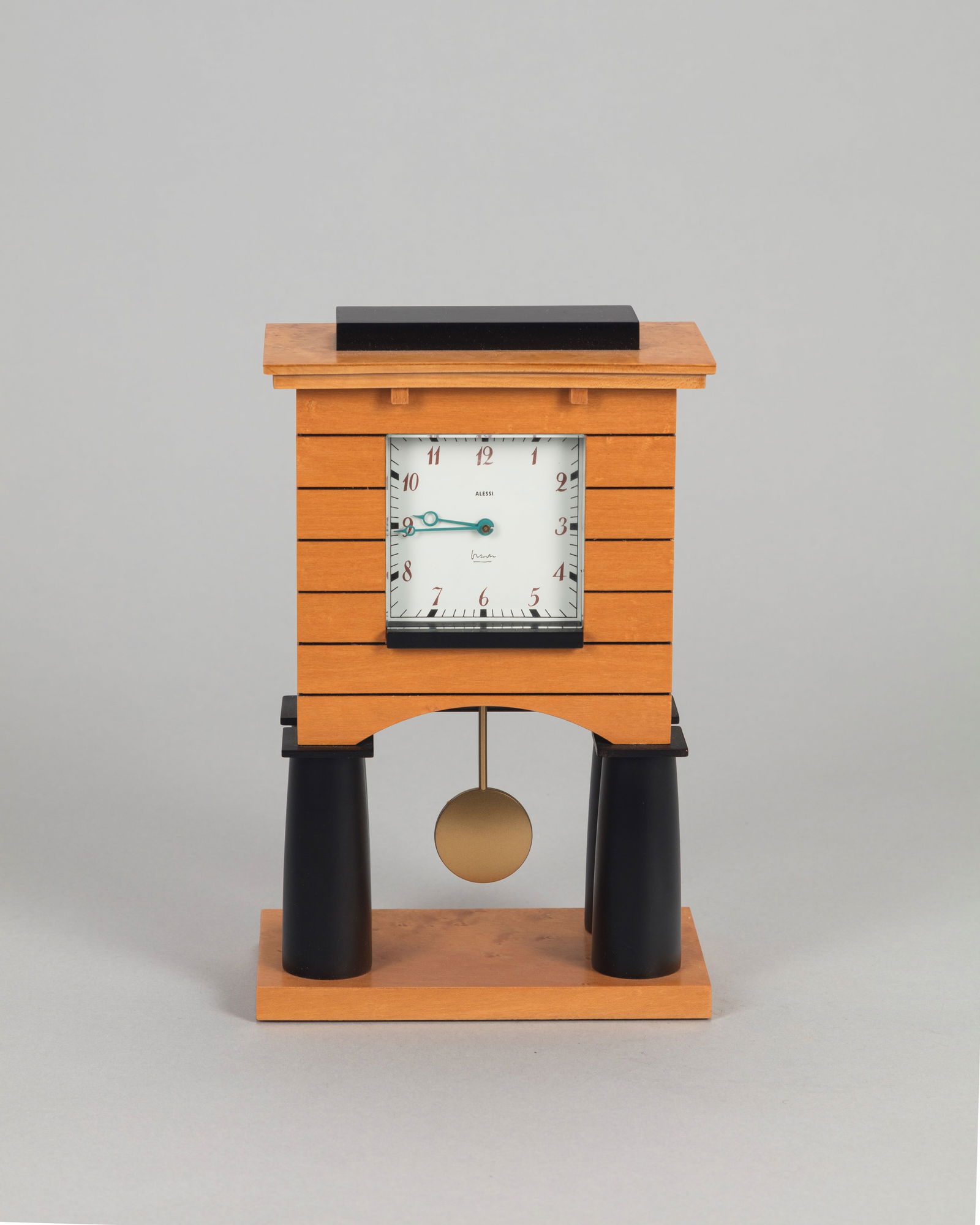 Michael Graves - Mantle clock, 1988 ca.: h 23,5 x 15,5 x 9,5 cm in veneered wood and ABS.Maple veneer, quartz movement.Prod. Alessi