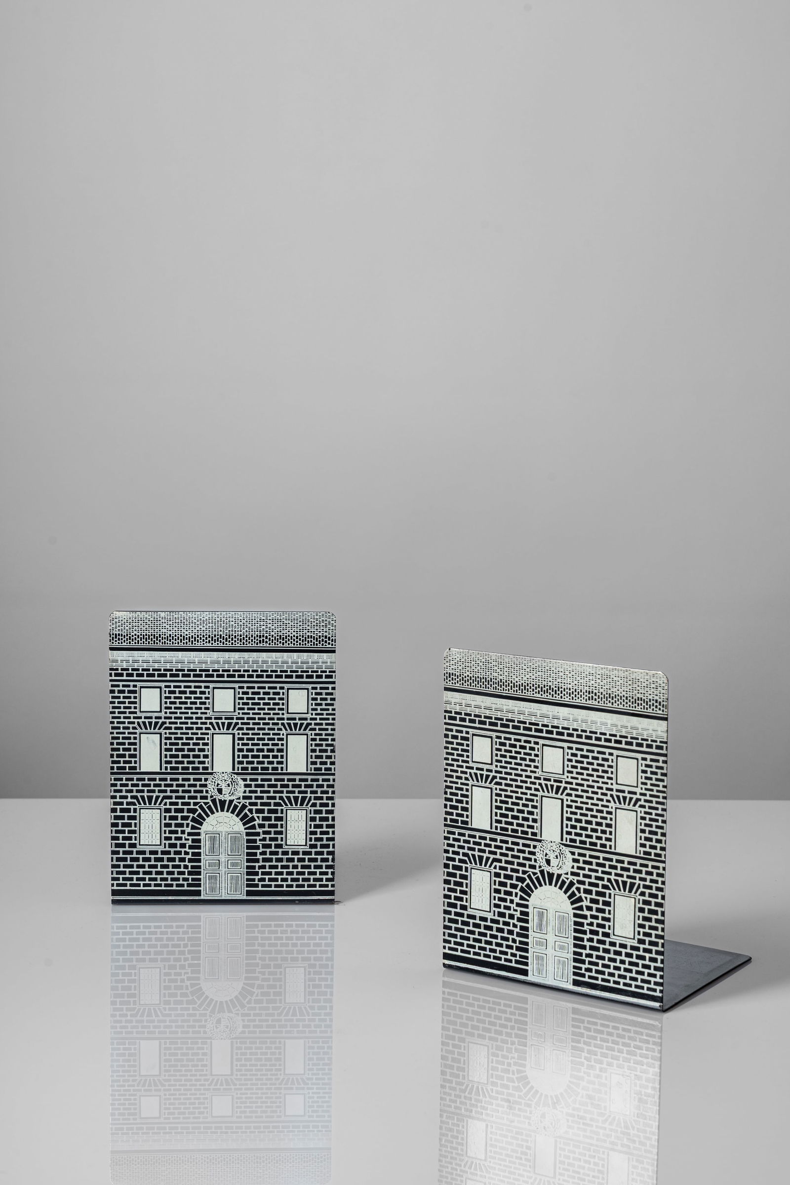 Piero Fornasetti (Milano 10/11/1913 - Milano 09/10/1988) - Pair of bookends, decoration: 20,4 x 15 x 13 cm Pair of bookends with silk-screen 'Architettura' (negative) printed decorationMetal screen printed, clothOriginal logo FORNASETTI - MILANO/ MADE IN ITALY under the baseFornasetti edi