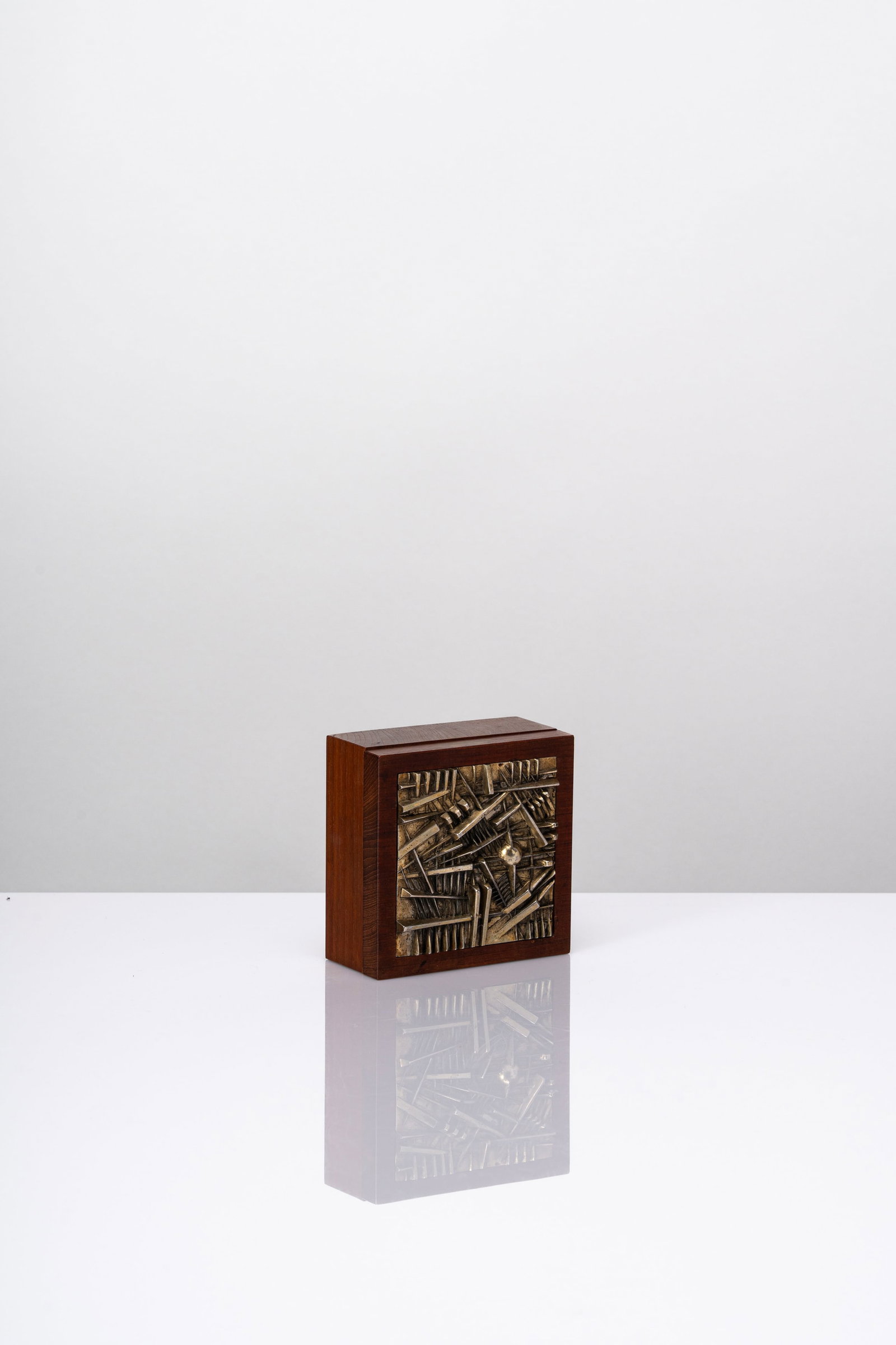 Arnaldo Pomodoro (Morciano di Romagna 1926 - Milano 2025) - Scatola per Ciga Hotels, 1980: cm 5 × 11.5 × 11.5 designed in 1980silvered bronze, woodlimited edition of 520 pieces (500 in arabic numbers + XX in roman numbers and some P.A.)signed with fire ARNALDO POMODORO / CIGAHOTELS on