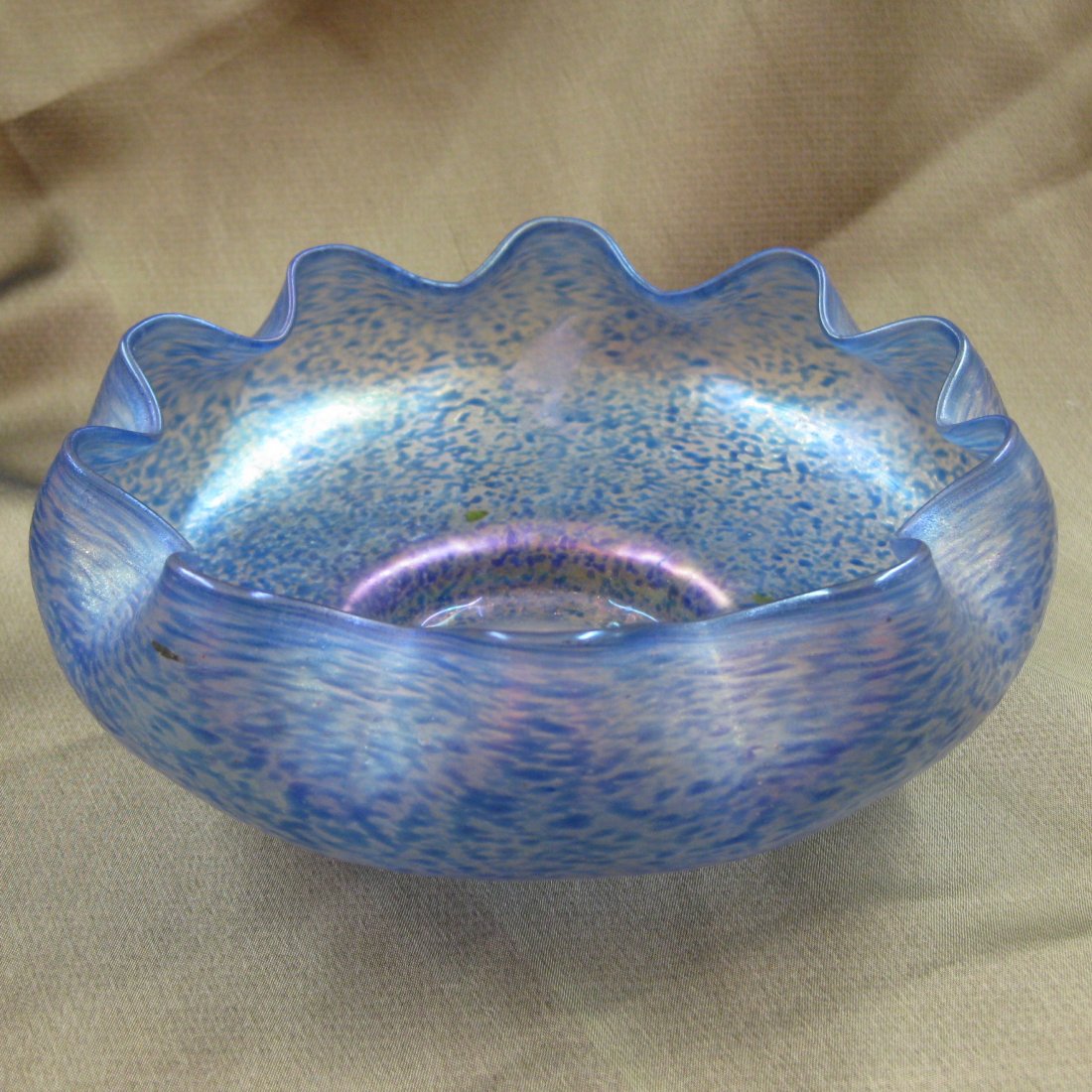 Loetz Iridescent Blue Petal Bowl: Thia is a fabulous iridescent petal bowl that is mainly light blue with hints of green, purple and dark blue, made by Loetz. A squat orb shape with a ruffled rim that closes in on itself. The piece is