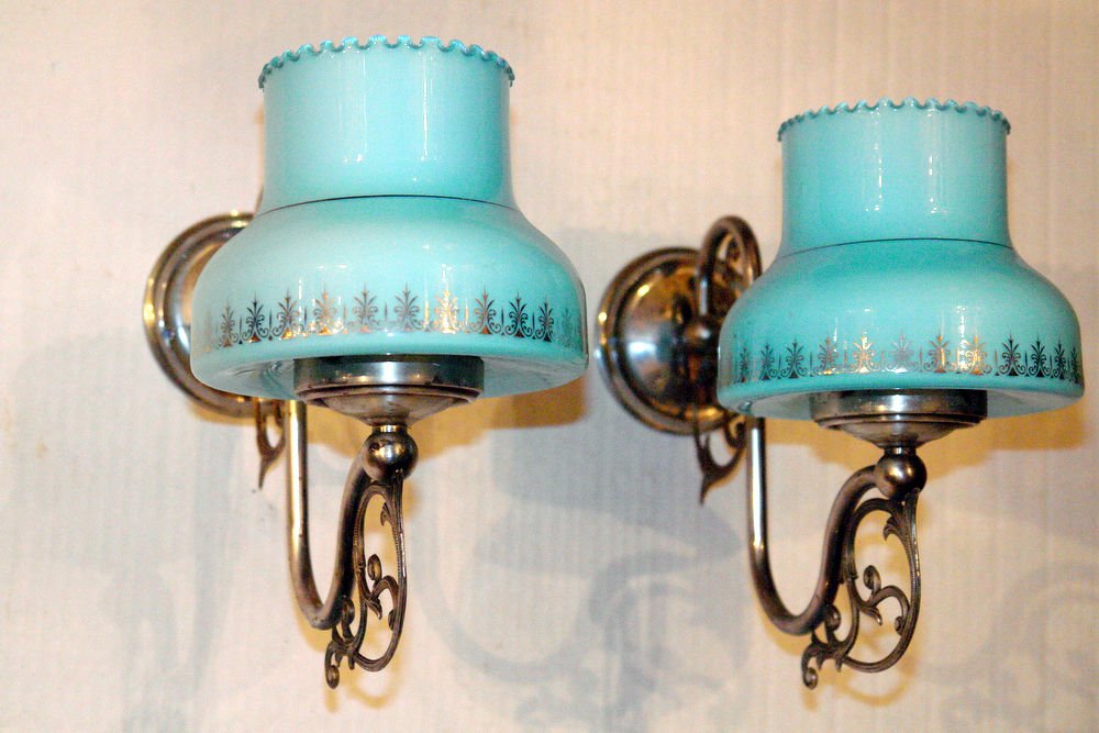 PAIR OF BLUE GLASS SHADE SCONCES: A pair of circa 1920’s English silver-plated single-arm sconces with original blue opaline glass shades with silver decoration. Measurements: Height: 10? Depth: 11? Width/length: 6? This item ships