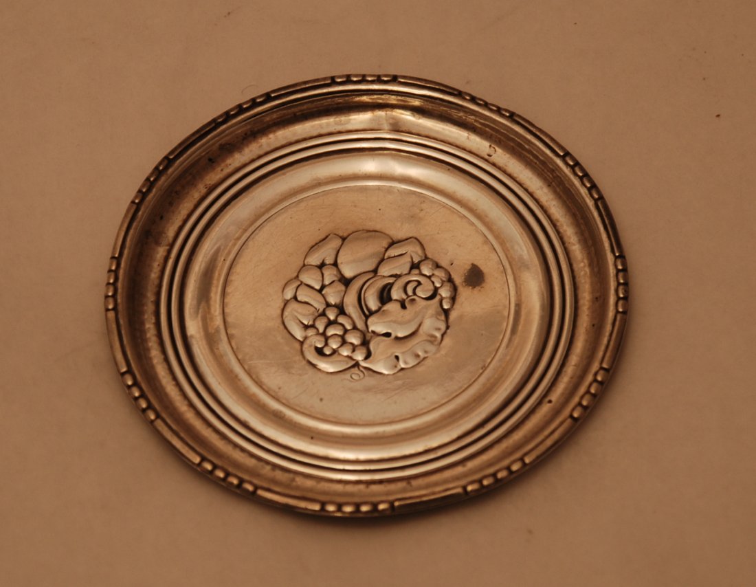 Georg Jensen Sterling Silver Wine Coaster #41: Georg Jensen Sterling Silver Wine Coaster #41 with floral grape decoration embossed in the center. Measuring 3 and 1/4 inches in diameter. Bearing pre-war marks as shown. Please note that this lot has