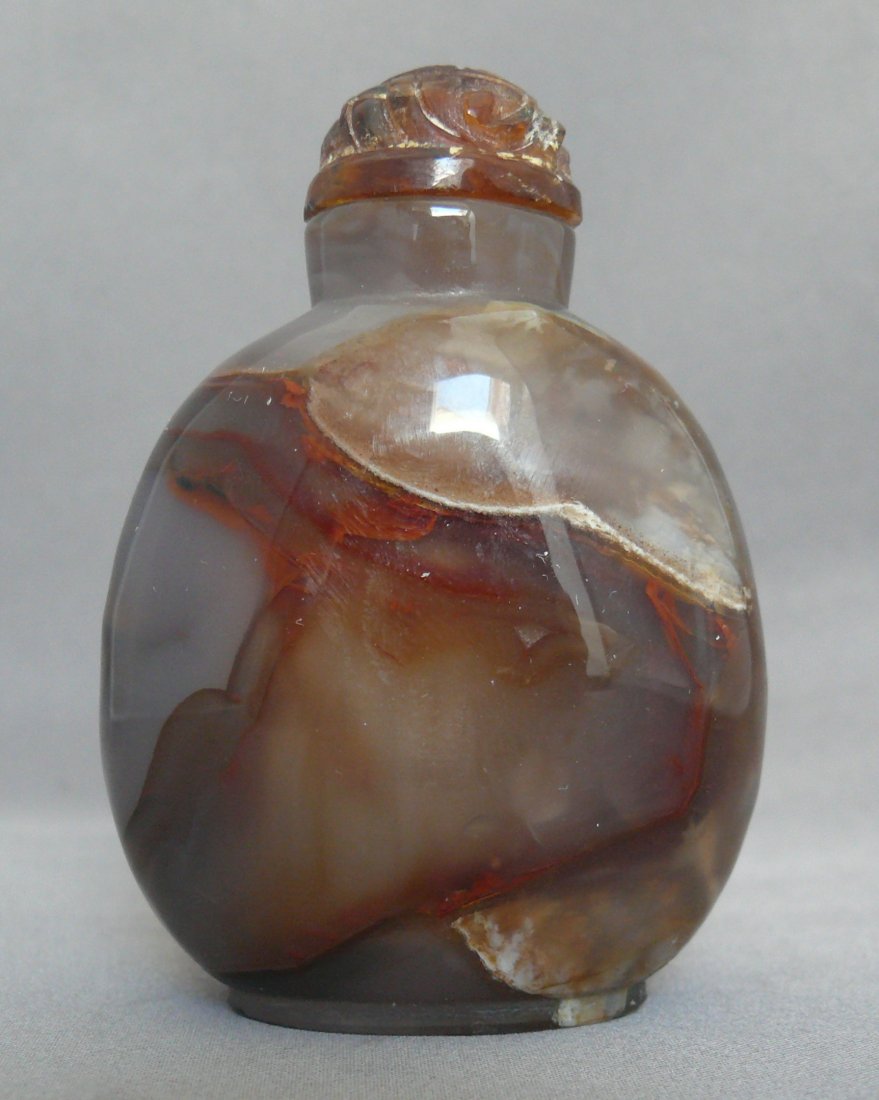 Banded Agate Snuff Bottle With Tortoise Cap: The agate bottle is of compressed form with a slightly concave lip and an oval bottom with a slightly raised foot. The cap is carved amber and the spoon is bone. The alternate bands of dark and light