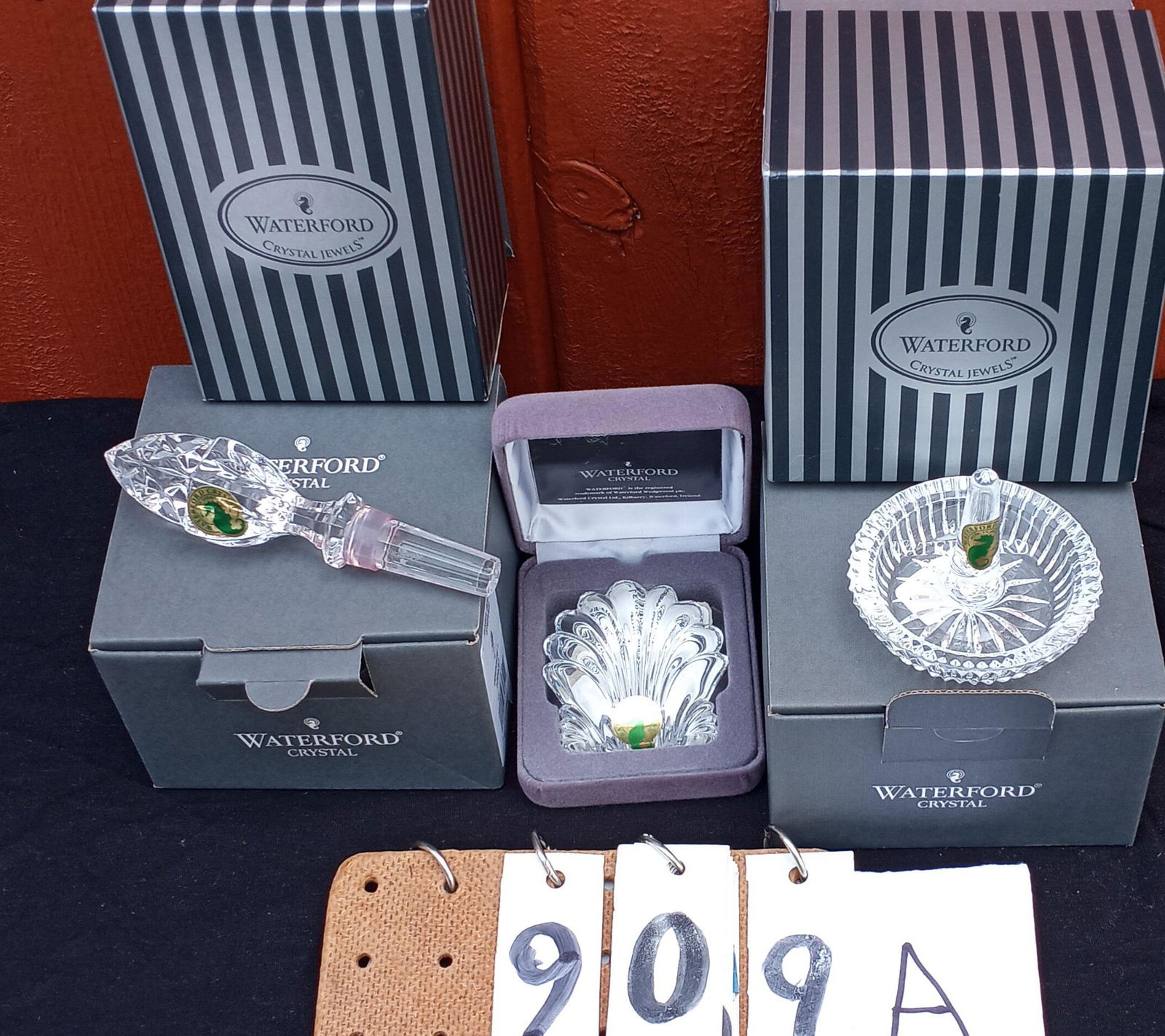 Three Miscellaneous Signed Waterford Pieces: Three miscellaneous signed Waterford pieces. One shell paperweight in original box, never used. 2.5"w x 2.875"h. One stopper in original box, never used. 1.375"w x 5.25"h. One ring holder in original