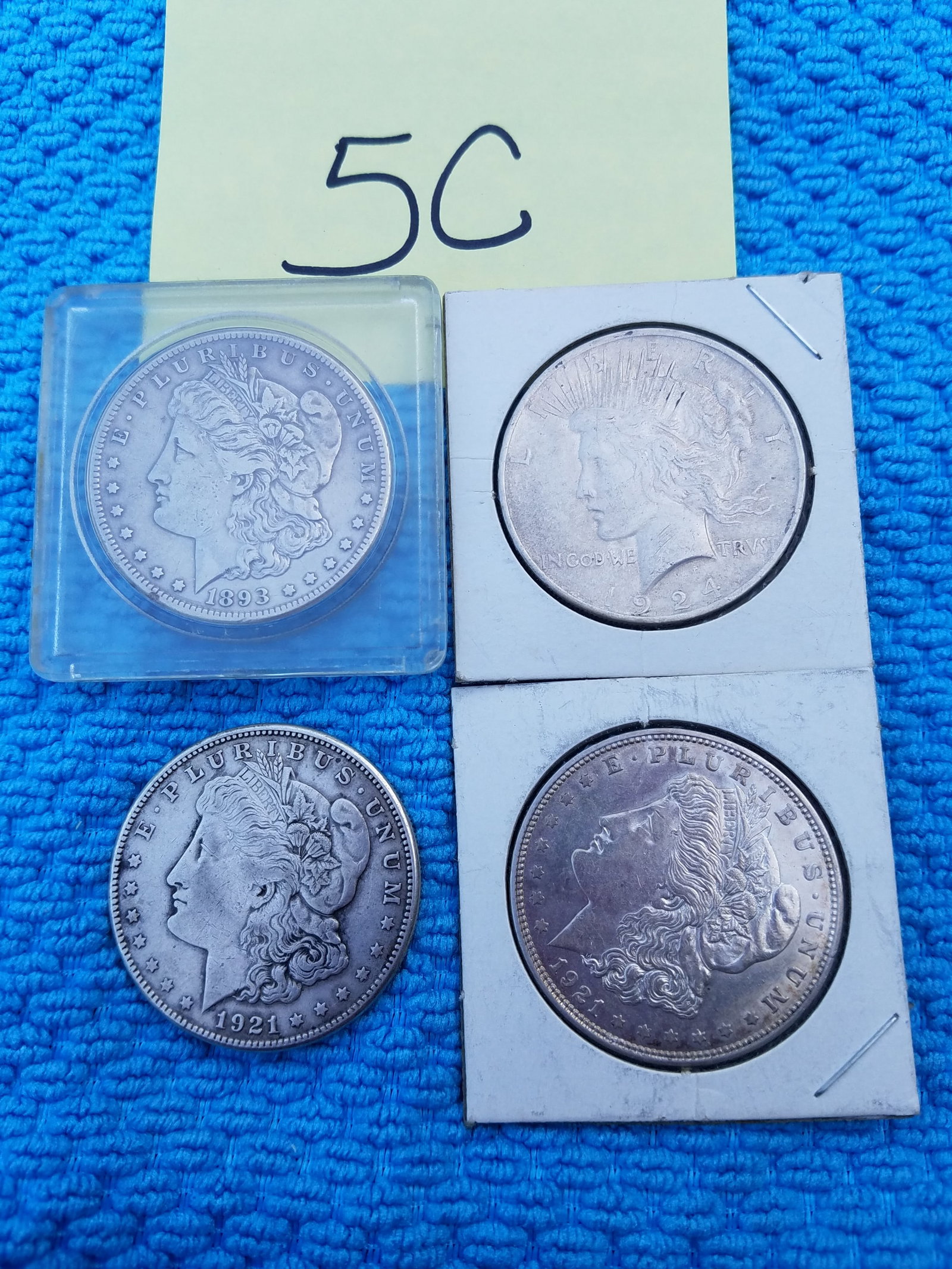 Four US Silver Dollars: Four US silver dollars. 1893-S Morgan, 1921-D Morgan, 1921-S Morgan and 1924 Peace. NOTE: The coin that photos as a 1893-S Morgan is actually a HIGHLY ALTERED/COUNTERFEIT COIN that has been heavilly r