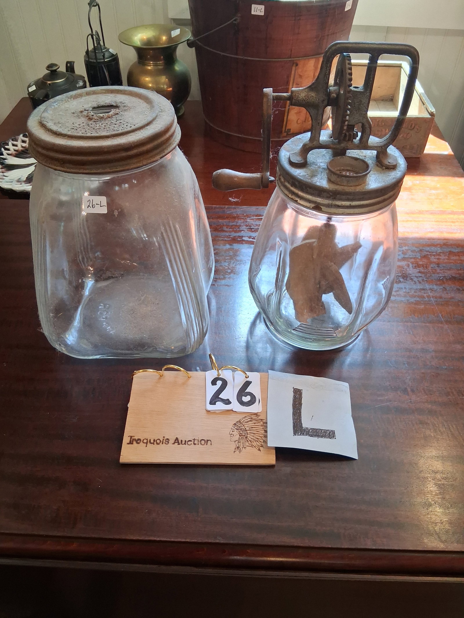 Two American Glass Jar Butter Churns: Two American glass jar butter churns. One butter churn with wood paddles - 8.5"w x 8.5"w x 14"h. One butter churn missing wood paddles - 8.5"w x 8.5"d x 11.5"h. See photos. Please read the Terms and C